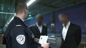Agente de la Police Nationale revisando documentos de dos hombres con rostros difuminados cSGnA3ctIJM