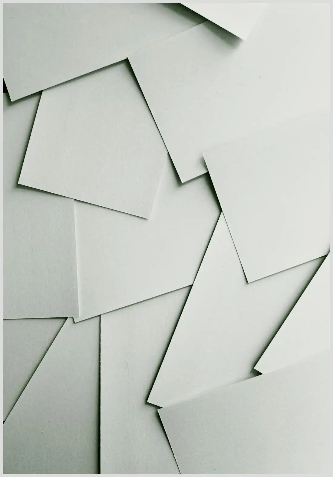 Planificadores digitales vs planificadores de papel: pros y contras que debes conocer, imagen de hojas de papel blancas superpuestas en ángulos geométricos que evoca planificación en papel